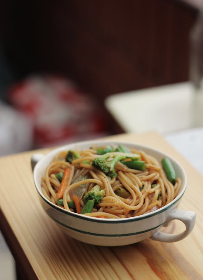 Vertical shot of savory veggie noodles in a ceramic bowl, perfect for Asian cuisine lovers.